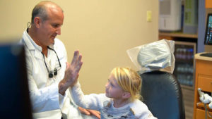 Dr. Annicchiarico high-fiving a young patient after their dental appointment